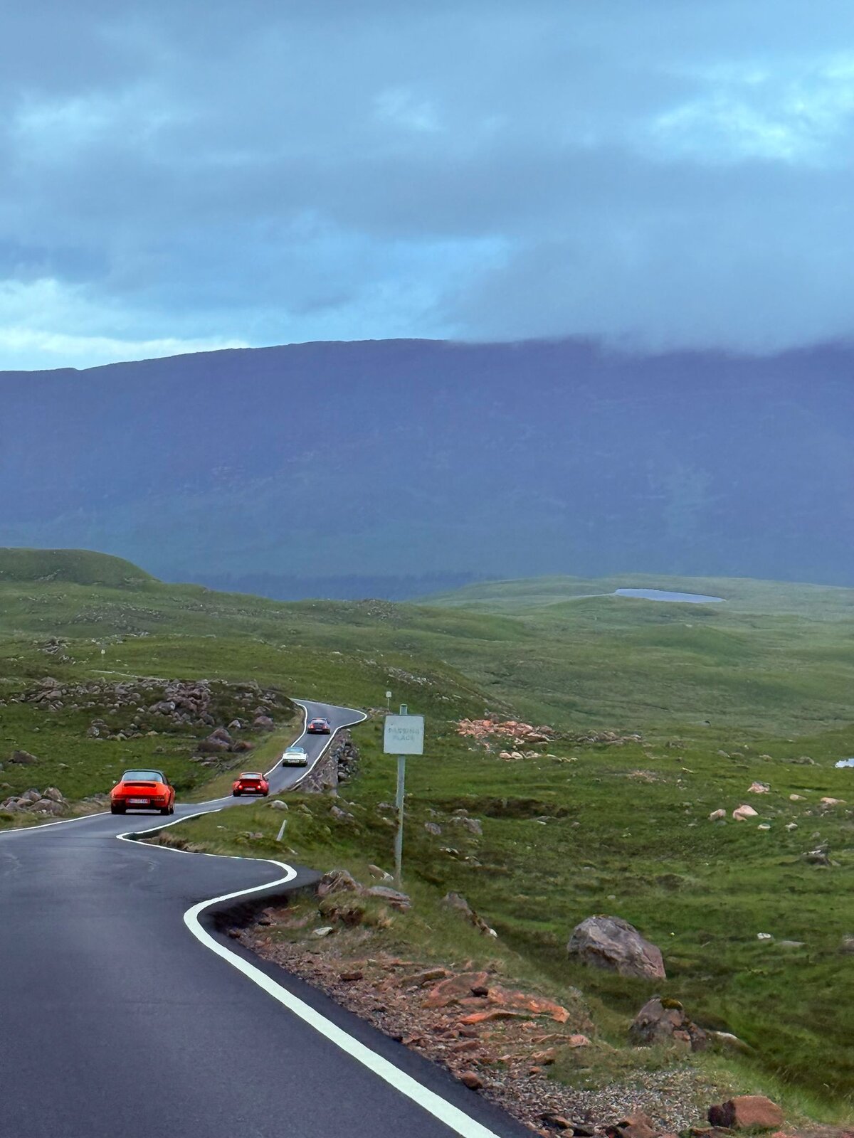 Porsche-Konvoi auf der NC500 mit Wolken über den Highlands — Foto von Benno